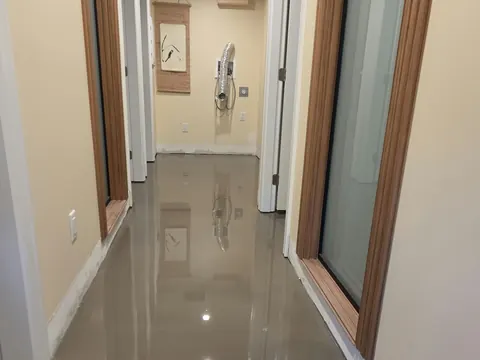 Basement hallway with freshly poured self-levelling underlayment reflecting the ceiling lights