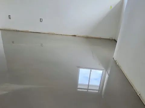 Upstairs bedroom with a fresh self-levelling pour reflecting the window